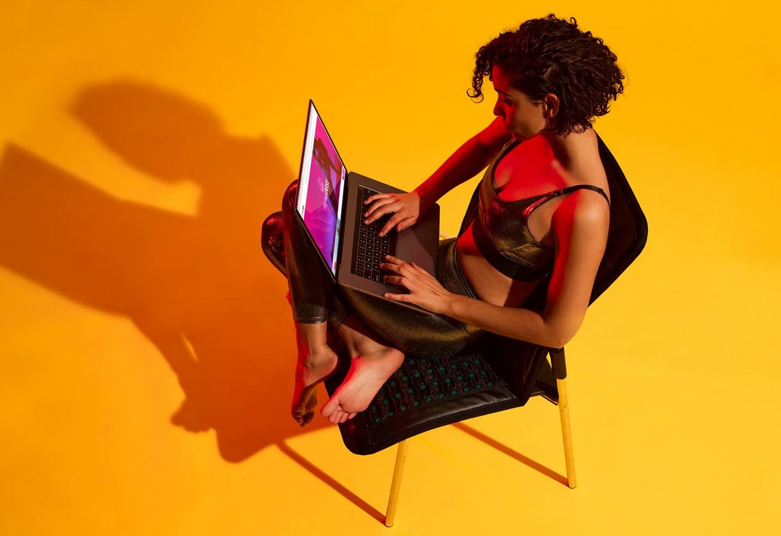 woman working on laptop while sitting on go mat